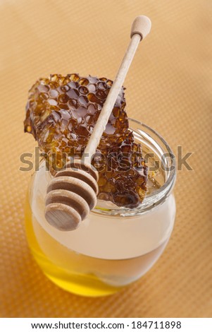 Golden organic honey in glass jar on golden honey comb. Natural organic honey concept. Healthy eating.