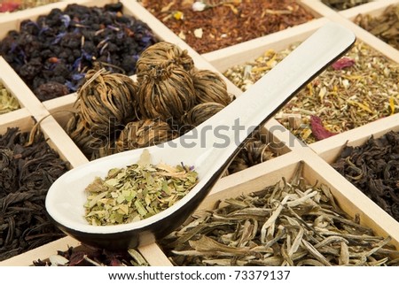 Dry tea variation in wooden box with tea spoon.