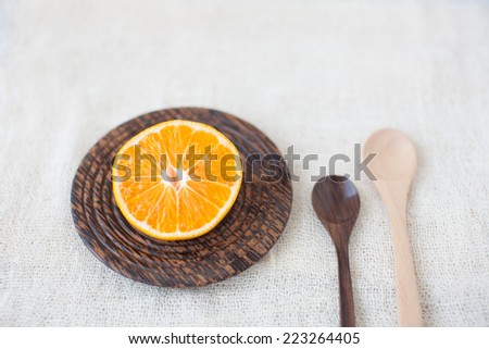 Orang on bottom plate and wooden spoons on white fabric