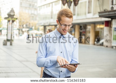 Smiling Businessman Using Tablet Computer on street in public space