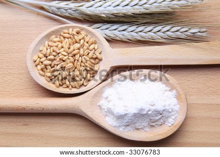 Grains of wheat and flour isolated on wooden background