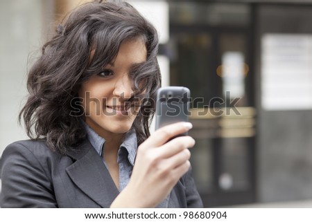 Young Woman photographing with mobile phone, background is blurred building