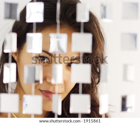 beautiful young woman hiding behind mirrored hanging beads