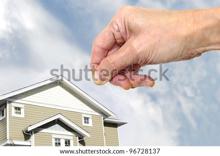 real estate home ownership investment  to buy as retirement income property . a hand pick a house with sky background