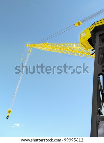 industrial construction derrick with hanging wire cable hoist on tall steel tower and blue sky background