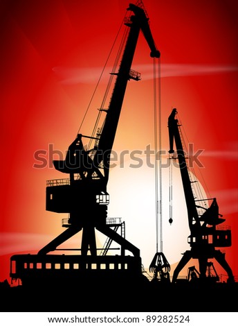 Silhouettes of two port cranes on a sunset