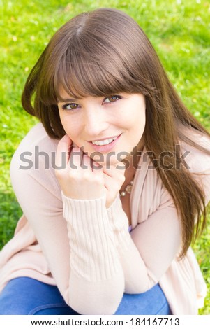 Happy young woman with hand on chin in pink cardigan sweater