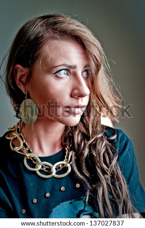 Close-up face Fashion women brunet beauty portrait  with a massive gold chain on her neck. Sha have sad blue eyes.