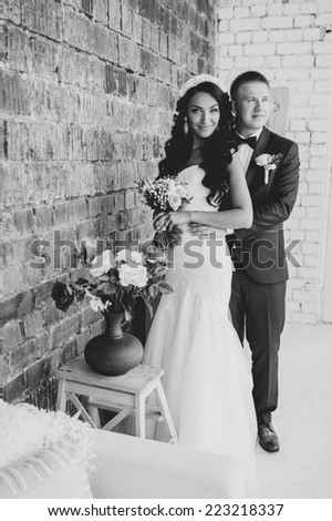 cute wedding couple in the interior studio decorated red brick. hey kiss and hug each other