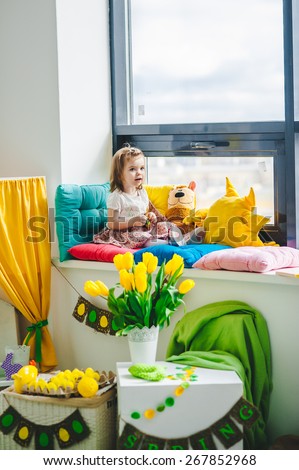 baby girl sitting near the window, smiling, easter decor