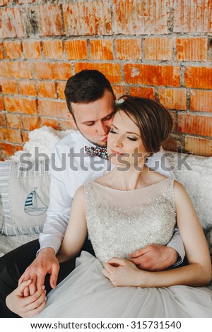 Beautiful young wedding couple is kissing and smiling in indoor. decorating studio.