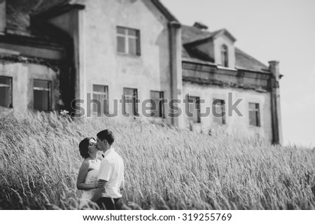 Beautiful bride and groom standing in grass and kissing. Wedding couple fashion shoot