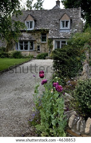 English cottage home with poppies growing at the entrance of the drive