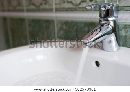 water tap with flowing water in modern bathroom