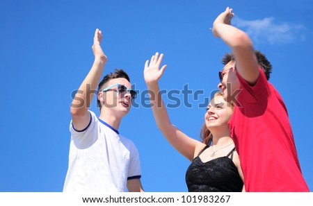 Three happy friends  Teenage boys and girl giving a five, outdoor against summer blue sky