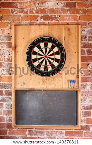 Dartboard on brick wall with chalk board score board and darts.