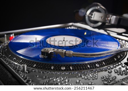 Dj turn table with blue vinyl album with headphones at nightclub
