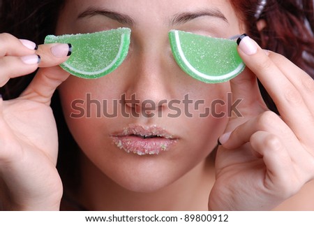 Woman holding 2 candy limes over her eyes with Candy on her lips