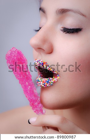 Woman with Candy sprinkle lips holding rock candy on a stick