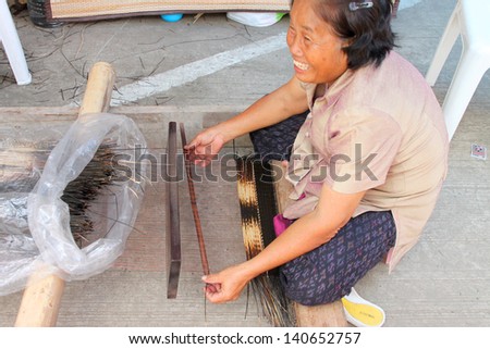 BURIRAM, THAILAND - SEPTEMBER 9 : Unidentified woman is weaving dried sedge mat  on September 9, 2012 in local trade fair, Muang, Buriram, Thailand. Mat weaving is rural traditional manufacturing.