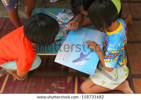 MAHASARAKHAM, THAILAND - OCTOBER 17 : Unidentified children aged 6-10 years are reading a book in public healthy mobile project at Non Mi village on October 17, 2013 in Muang Mahasarakham, Thailand.
