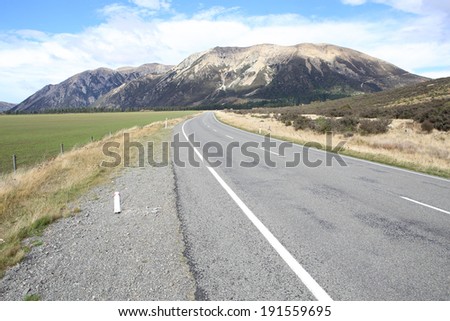 One beautiful road with alpine mountain background in the countryside of New zealand in Autumn season.