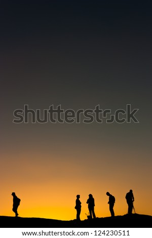 A group of people in silhouette against an orange desert sunset