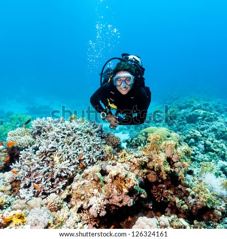 Smiling female scuba diver underwater on a coral reef