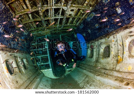 A SCUBA diver explores the upturned cabin of an underwater aircraft wreck