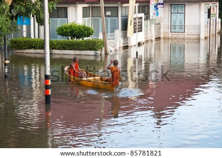ANGTHONG - SEPTEMBER 17 : Monks oaring plastic boat through deep water during water flooding in Thailand, on Sept 17, 2011 in Angthong, Thailand