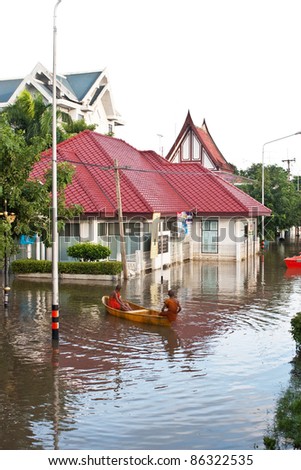 ANGTHONG - SEPTEMBER 17 : Unidentified monks paddle a plastic boat through deep water during water flooding in Thailand on Septemember 17, 2011 in Angthong, Thailand