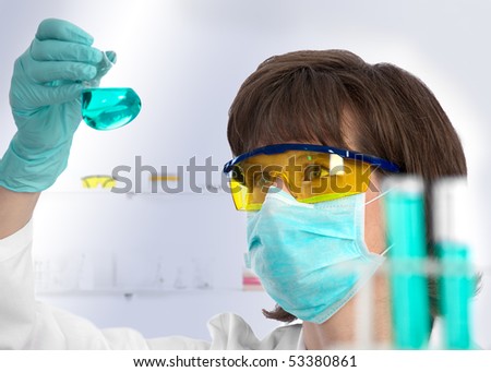 Closeup of a female scientist examining the green liquid contents of a conical flask in the lab