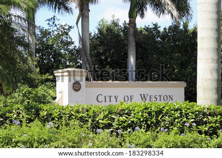 WESTON, FLORIDA - OCTOBER 22, 2013: Entrance sign to the city of Weston, Florida, located in western Broward County, with beautiful flowers in front and tropical foliage behind on a sunny day.