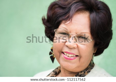 Portrait of happy old african american woman with glasses and wig smiling at camera