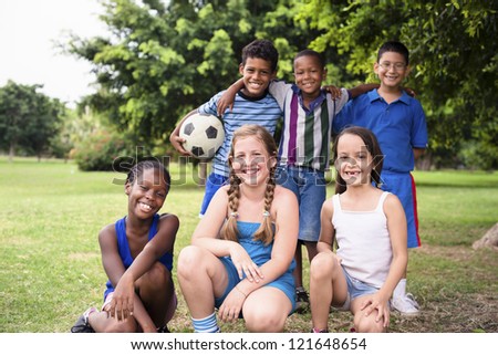 Young boys and sport, portrait of three young children with football looking at camera. Summer camp fun