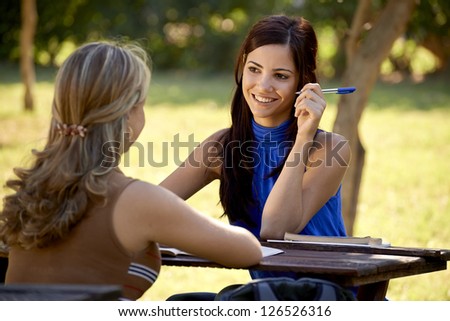 Young women at school, two female friends talking and studying for college test in park. Sequence of medium and wide shots