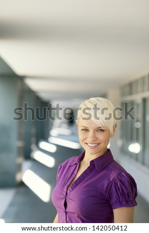 portrait of confident attractive business woman smiling and looking at camera out of office building. Copy space