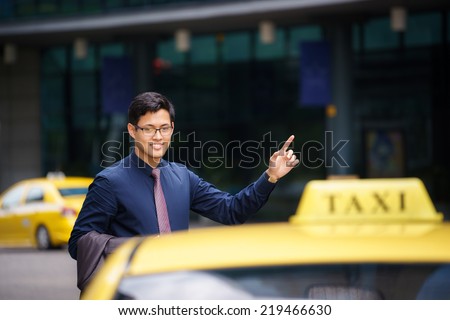Asian business man standing near office buildings, calling yellow taxi and entering in car