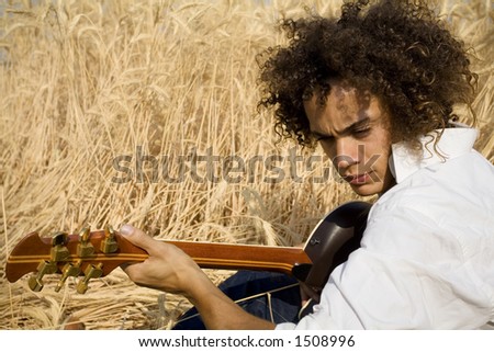 cool guy laying in a cornfield playing guitar