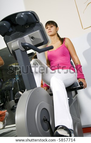health club: young girl working out on a cyclette