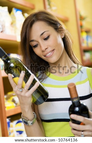 woman in a supermarket comparing two wines