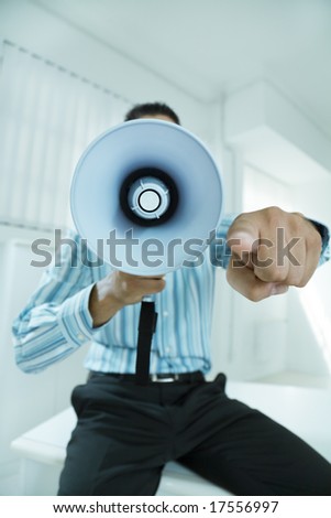 young businessman in office screaming on the megaphone