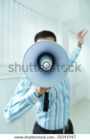 young businessman in office screaming on the megaphone
