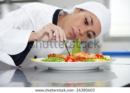 mid adult female chef in kitchen decorating dish