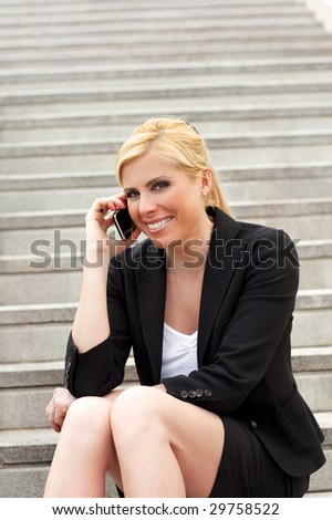 portrait of mid adult businesswoman sitting on steps and talking on the phone. Copy space