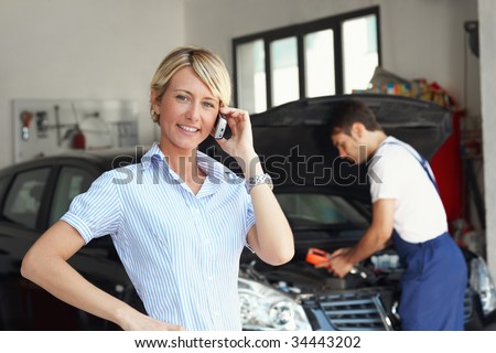 portrait of female client talking on mobile phone in auto repair shop.