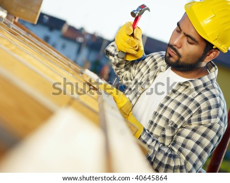latin american construction worker on house roof with hammer. Copy space