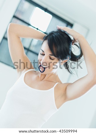 woman tying hair with rubber band in mouth