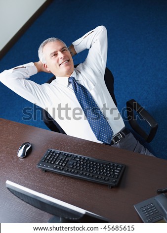 Mature business man leaning on chair with hands behind head, looking away and smiling. Copy space
