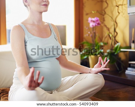 cropped view of italian 6 months pregnant woman sitting with crossed legs doing yoga exercise at home. Horizontal shape
